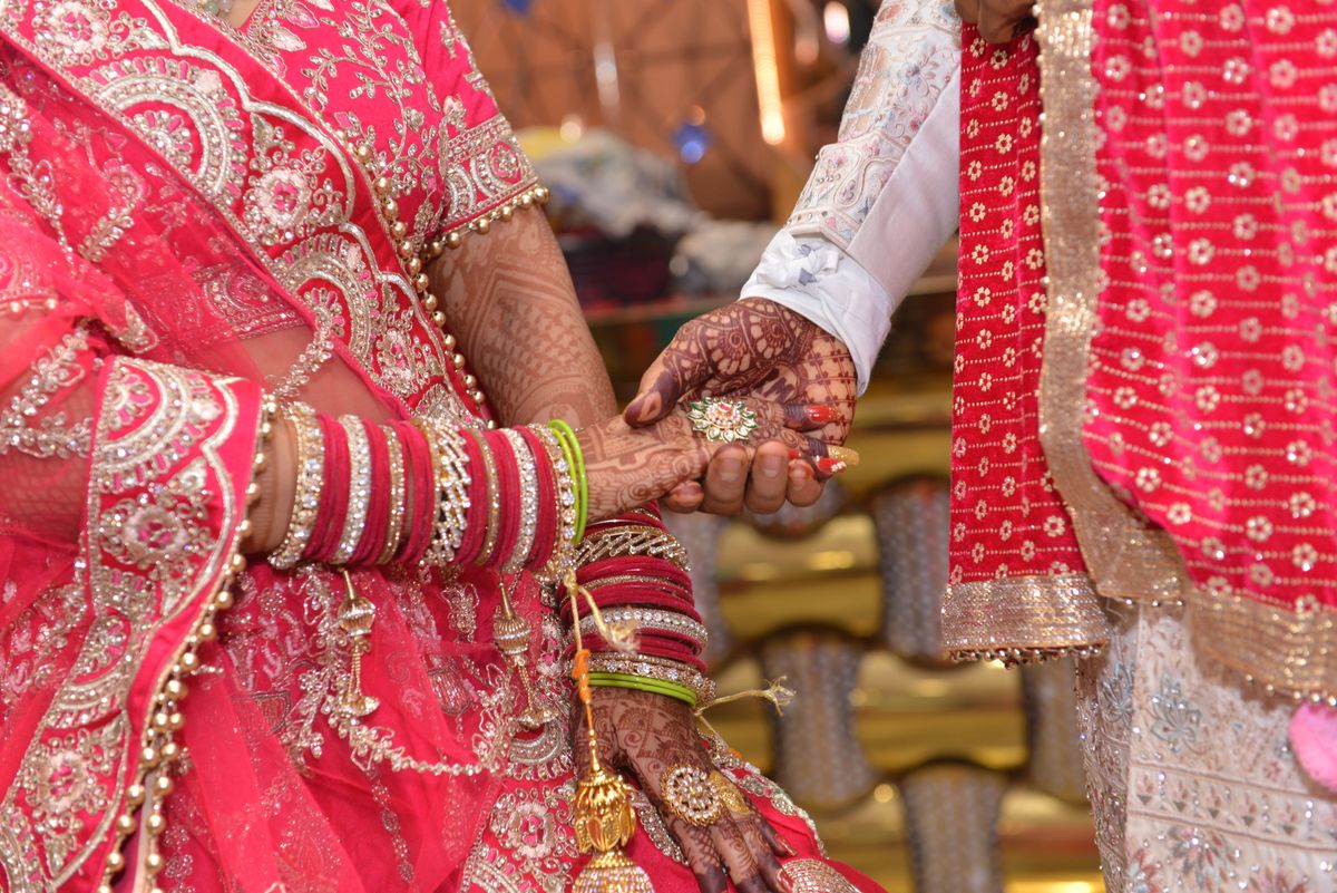 Bride and groom's hands joined, mehendi and chooda in close view
